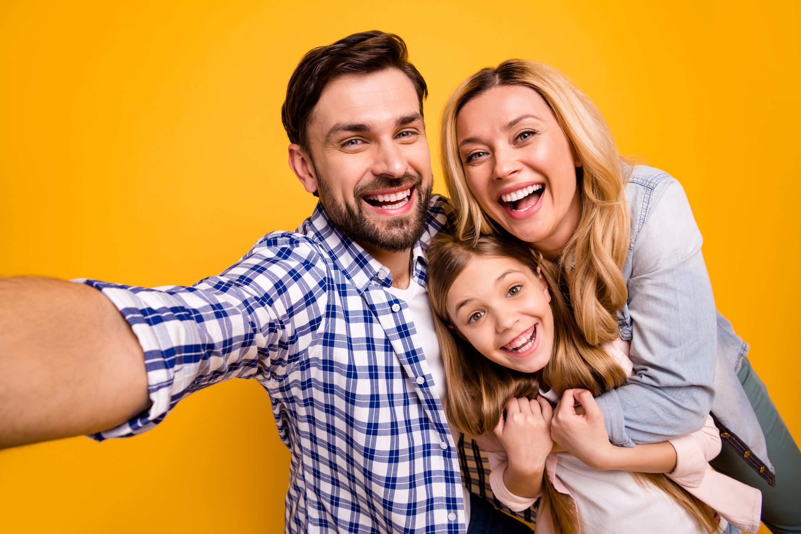 Familie de millenniali fericită care se filmează pentru TikTok pe un fundal galben.
